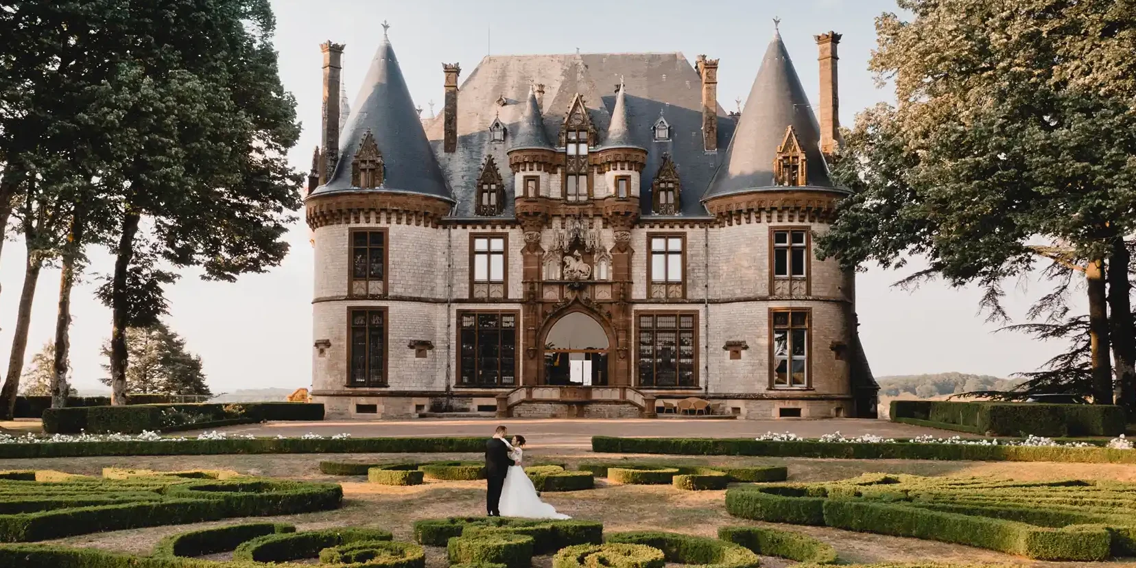 Impressive French chateau with couple stood in the garden. Chateau Bournel